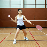 **Intense badminton practice session:** A badminton player focused on technique, practicing strokes on the court. Gym setting. Emphasis on dedication and hard work.